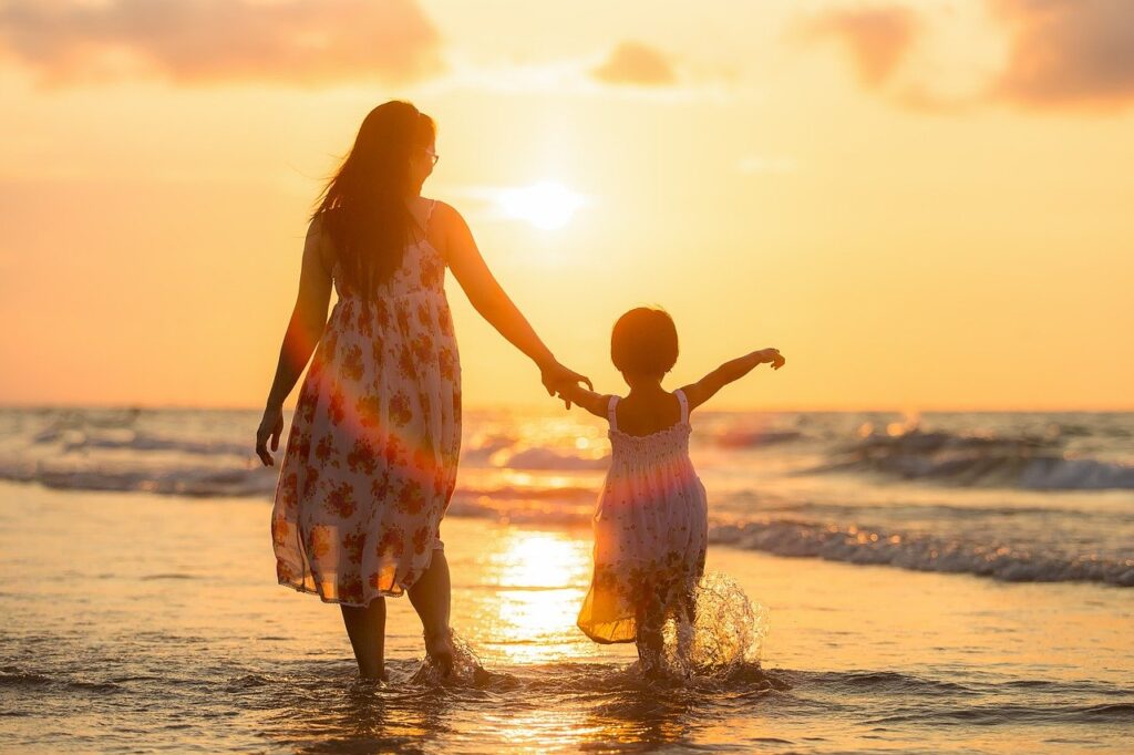 手を繋いで海を歩く家族